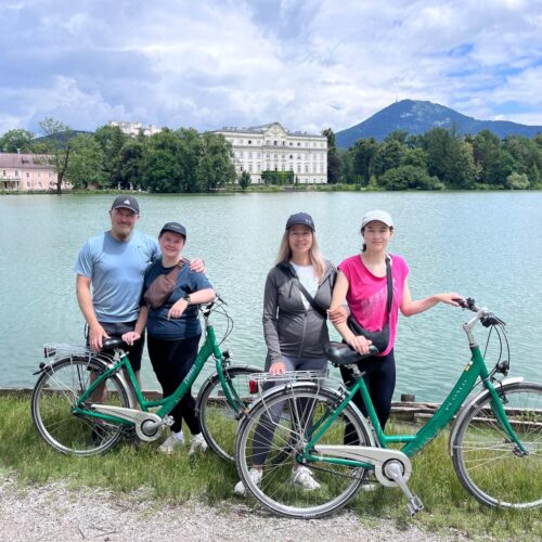 Family enjoying Sound of Music e-bike tour in Salzburg with scenic Leopoldskron Palace in background