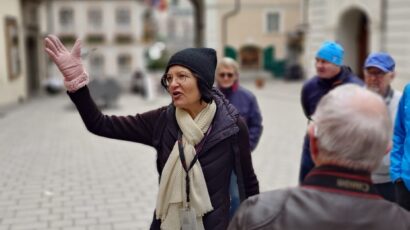 Certified tour guide Annabelle Blanc leading a private Salzburg walking tour for a small group of tourists in a historic courtyard in Salzburg City, Austria.