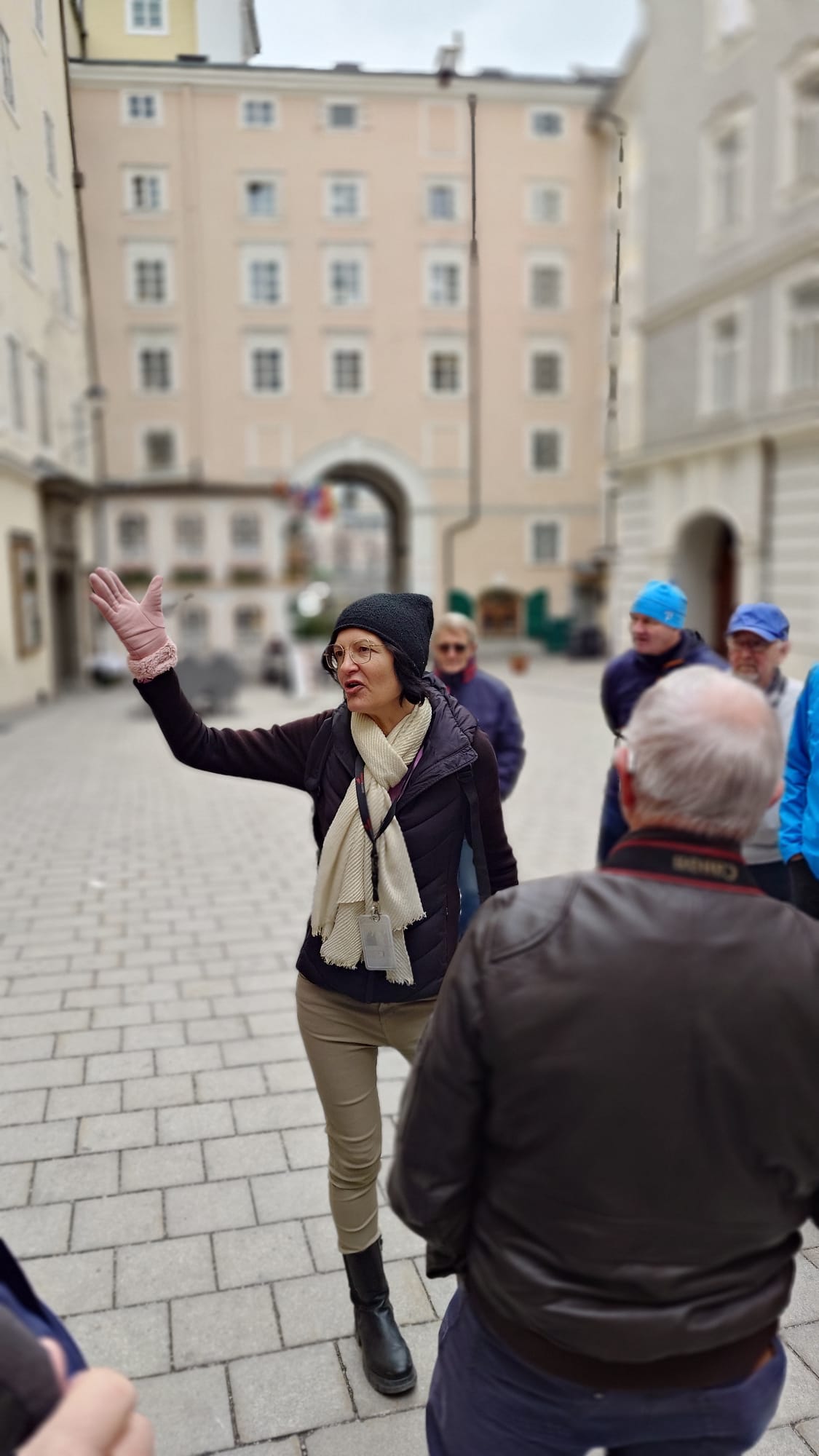 Certified tour guide Annabelle Blanc leading a private Salzburg walking tour for a small group of tourists in a historic courtyard in Salzburg City, Austria.
