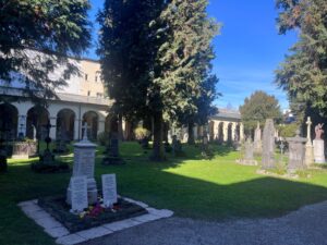 The historic Mozart family tombstone standing in the peaceful, sunlit green courtyard of the Sebastiansfriedhof during a St Sebastian cemetery guided tour in Salzburg, Austria.