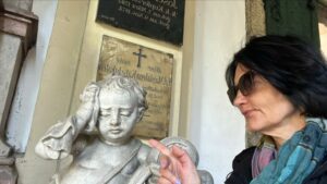 Certified guide Annabelle Blanc pointing to a beautiful weeping cherub marble statue during a private St Sebastian cemetery walking tour in Salzburg, Austria.