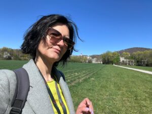Local guide Annabelle Blanc standing in a green field with Abbey Nonnberg in the distance, providing expert insights for the Sound of Music local bus tour Salzburg.