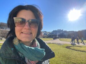 State-certified local guide Annabelle Blanc standing in the sunny Mirabell Gardens, ready to lead an exclusive Private Sound of Music City Walk.