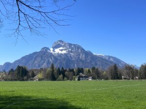 The majestic snow-capped peaks of the Untersberg mountain viewed from a lush green meadow in Salzburg, Austria, a view enjoyed on our Private Sound of Music public transit tour.