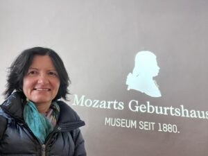 Expert local guide Annabelle Blanc standing next to the illuminated Mozarts Geburtshaus sign at Mozart's Birthplace, an essential stop on a comprehensive salzburg city walking tour.