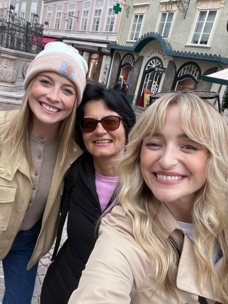 Certified guide Annabelle Blanc taking a selfie with two happy tourists in front of a traditional pharmacy building during a premium salzburg guided walking tour in Salzburg, Austria.